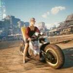 V sits on her motorcycle on the beach in Cyberpunk 2077